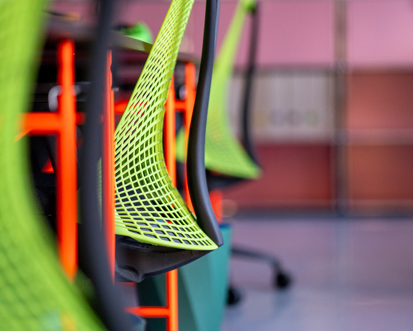 Moderne neon-grüne Bürostühle an neon-orangenen Schreibtischen im Büro der Kreativagentur buero_v1 in Düsseldorf